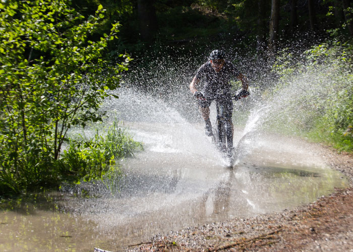 Mountainbiker fährt durch eine riesige Wasserpfütze